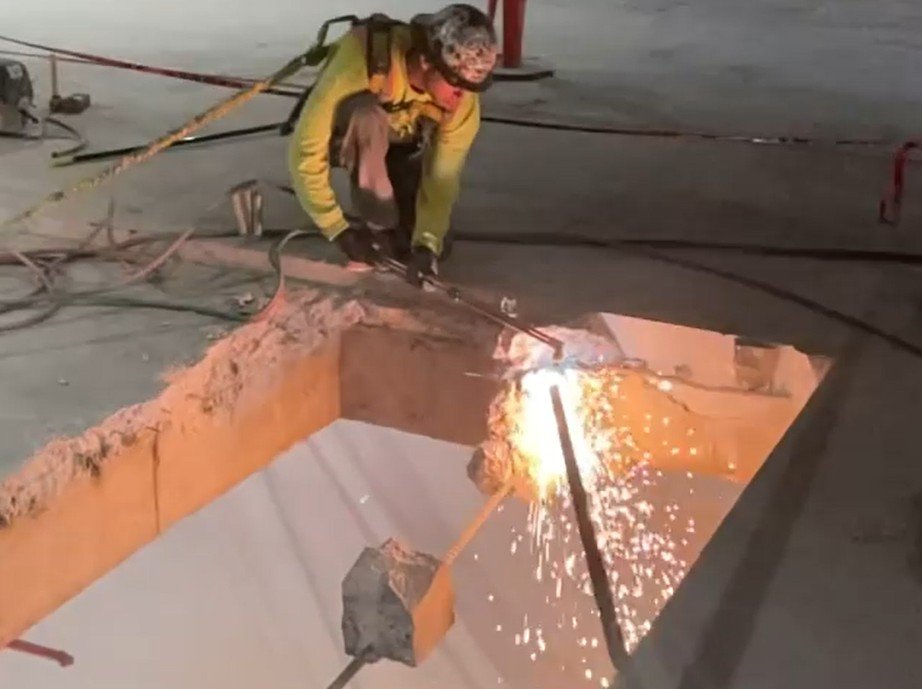 DSI compressor crew of three workers using pneumatic chipping hammers on concrete floor in gutted interior